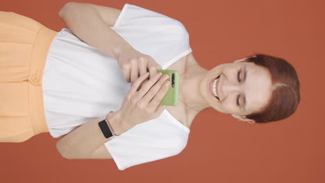 Vertical-video-of-Happy-woman-texting-on-the-phone.-Smiling.